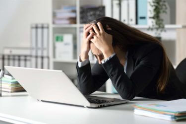 A woman looks frustrated while using a computer.